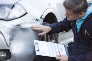 Insurance adjuster inspecting car damaged in accident