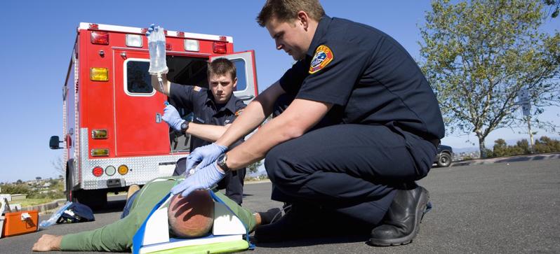 This image shows a seriously injured man on a stretcher with paramedics.