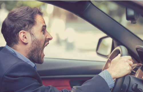 Angry young man screaming inside his car.